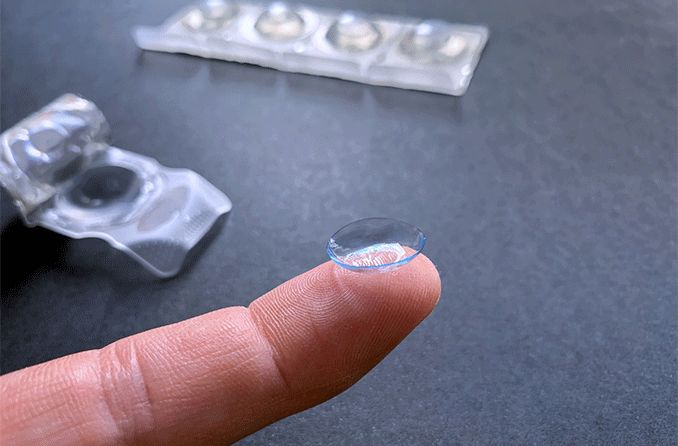 person hold cheap contacts on finger