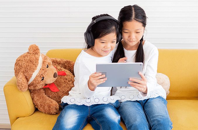 Two children looking at ipad on the sofa