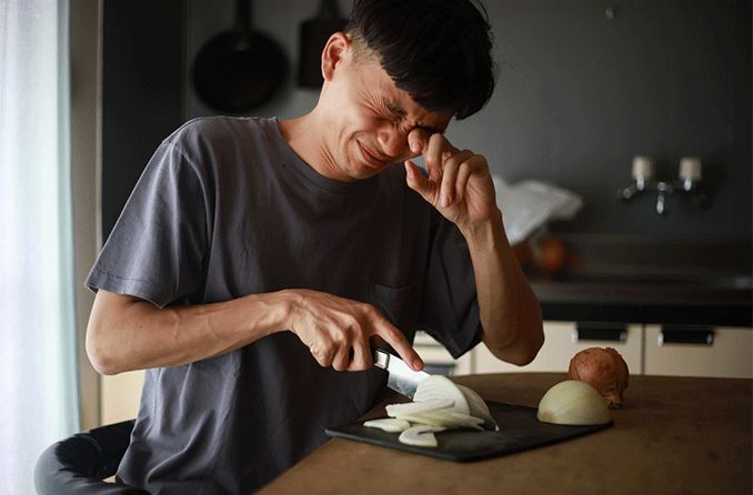man cutting onions and crying