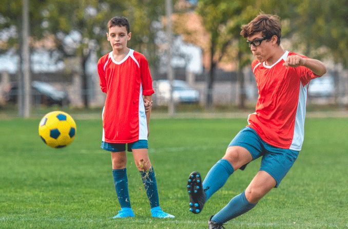 teen boy playing soccer and wearing sports glasses