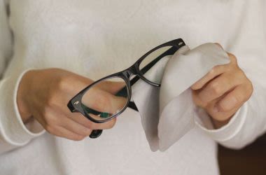Person cleaning glasses with cloth