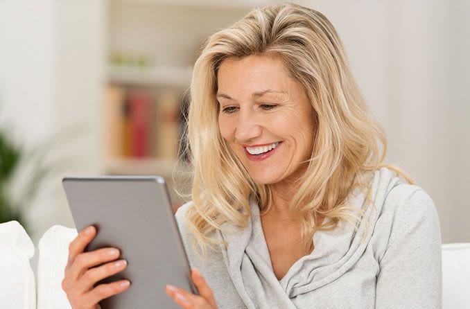 middle aged woman reading digital tablet