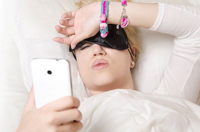 woman waking up in the morning with blurry vision looking at cell phone