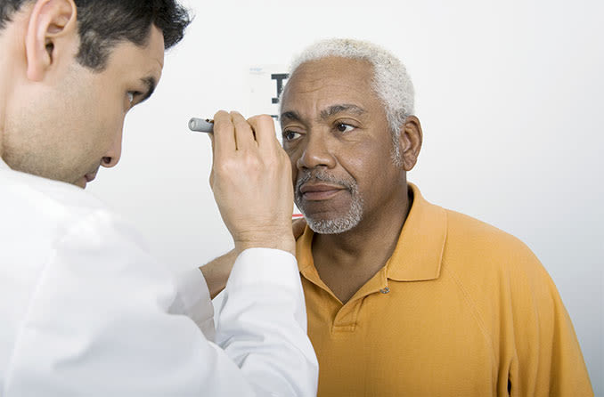 eye doctor looking at man's eye with cataracts
