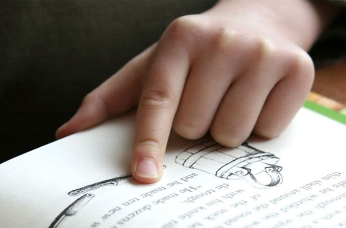 Child reading with their finger