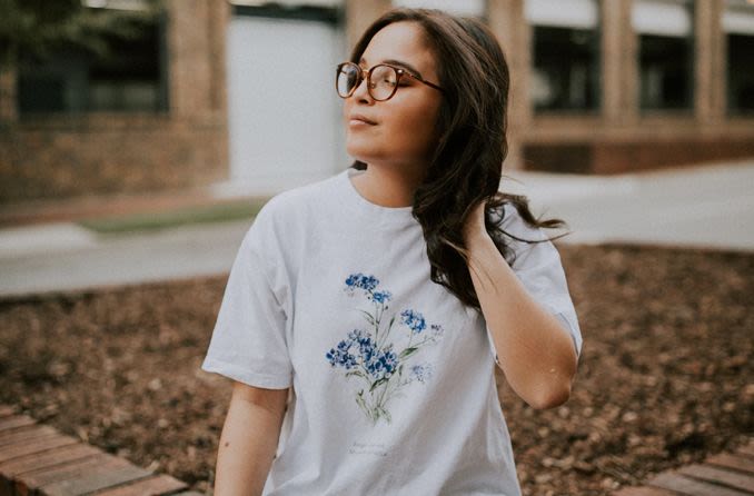 Menina de camisa branca e óculos de grau para correção da miopia.