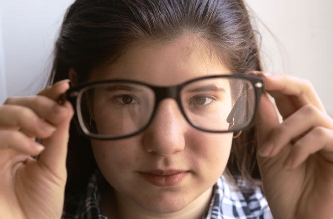 Fille tenant des lunettes et regardant à travers les lentilles