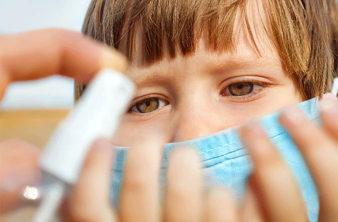 closeup of child's eyes looking at hand sanitizer being dispensed in his hands