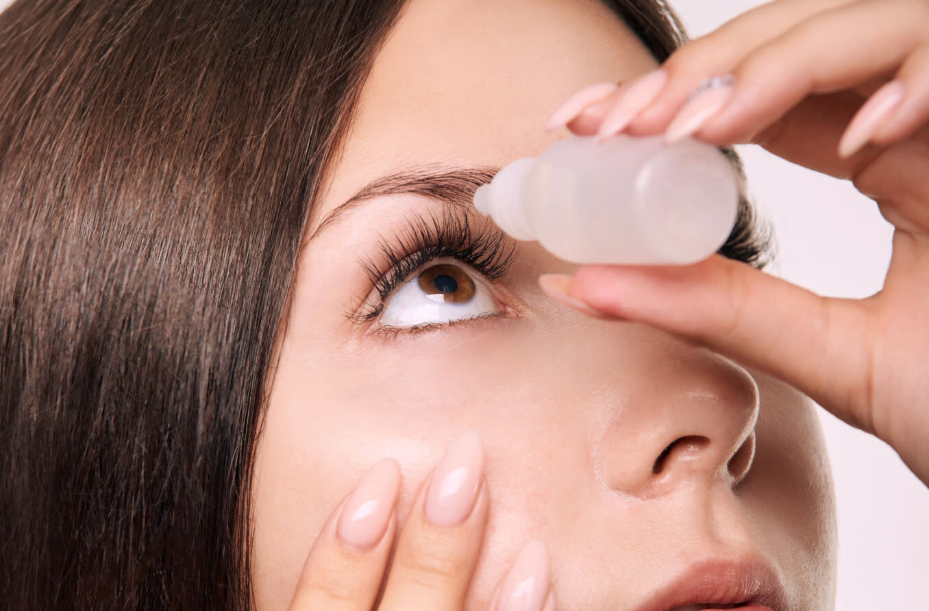 Woman putting eye drops into eye