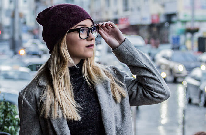 Woman holding her eyeglasses and looking off to the horizon.