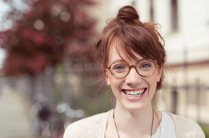 happy woman outdoors wearing round glasses