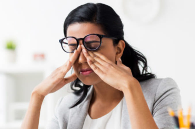  Mujer frotándose los ojos para lidiar con las contracciones del párpado provocadas por espasmos oculares