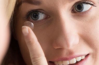 Woman placing contact lens on to eye