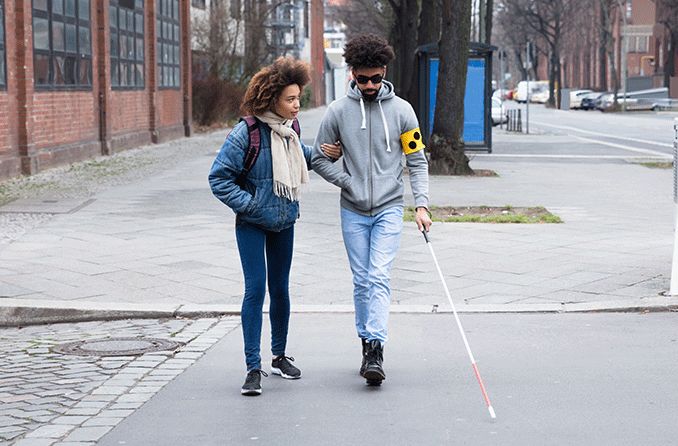 woman helping her blind friend walking with cane