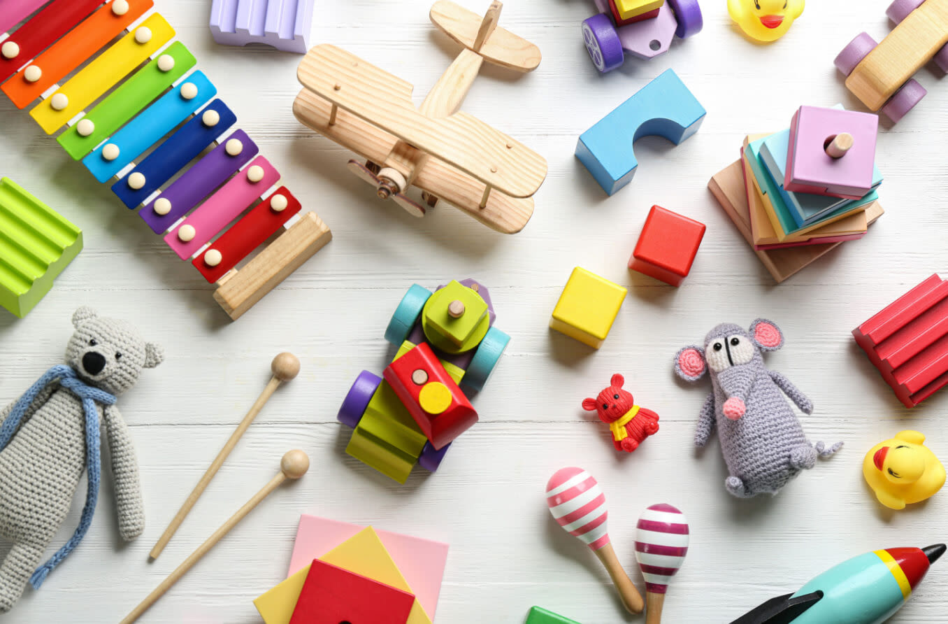 Different toys on white wooden background, laying flat.