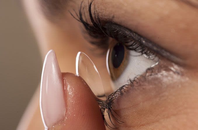 woman puts in contact lens