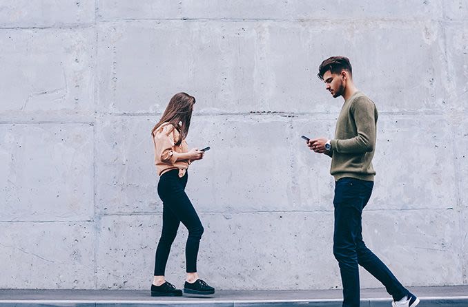 hipster couple looking at smartphones walking on the street