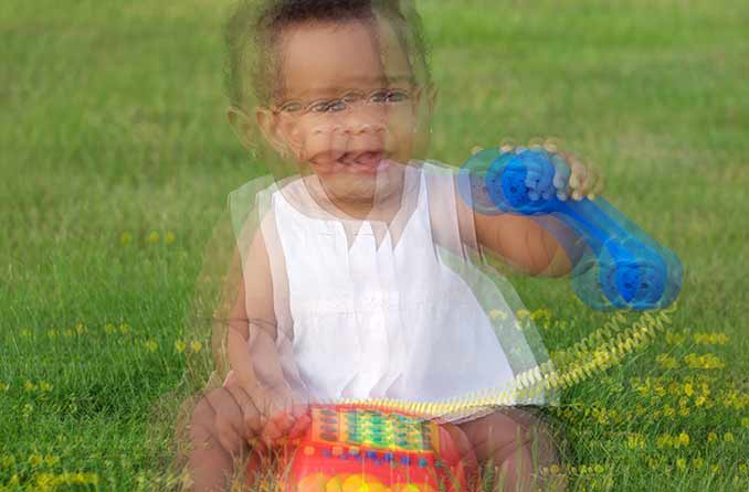 Simulazione di qualcuno con visione doppia (diplopia) che vede un bambino che gioca nell'erba.
