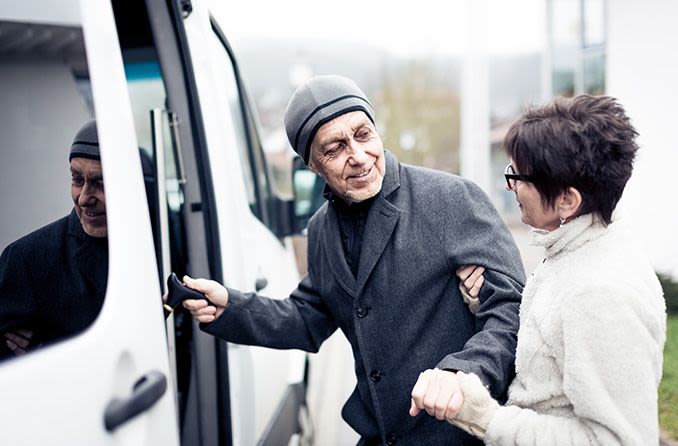 Woman helping an older man into a van
