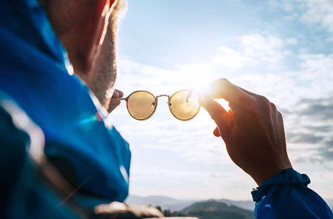 man looking through pair of sunglasses outdoors