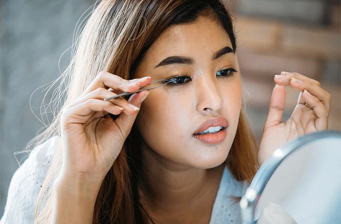 woman putting on her own eyelash extensions