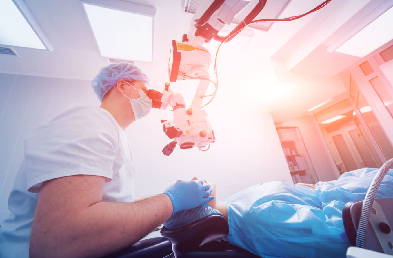 A patient and surgeon in the operating room during ophthalmic surgery.