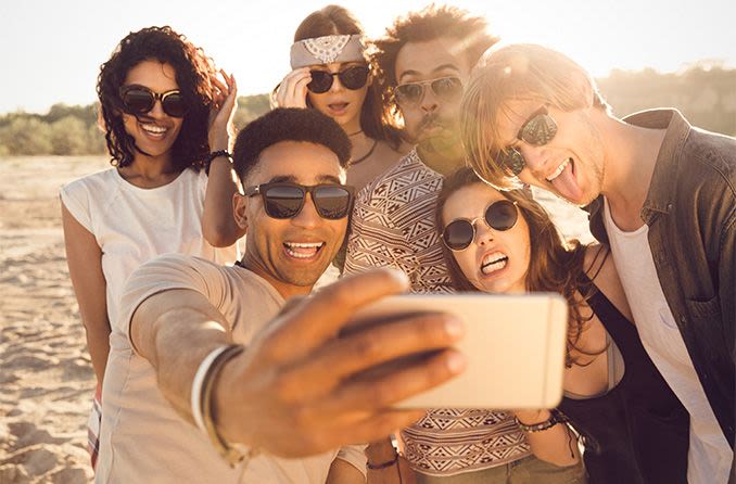 jeune groupe de personnes portant des lunettes de soleil sur la plage prenant un selfie