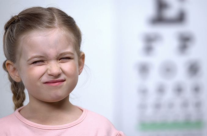 child squinting at eye chart