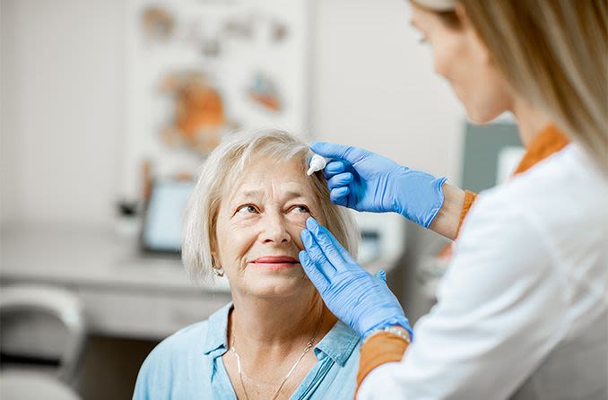 mature woman getting dilation eye drops inserted into her eye
