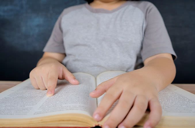 child reading book with finger