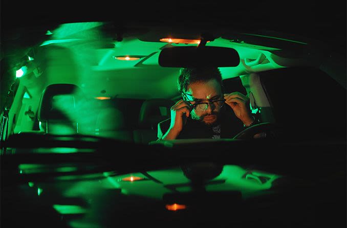 man driving at night putting on eyeglasses