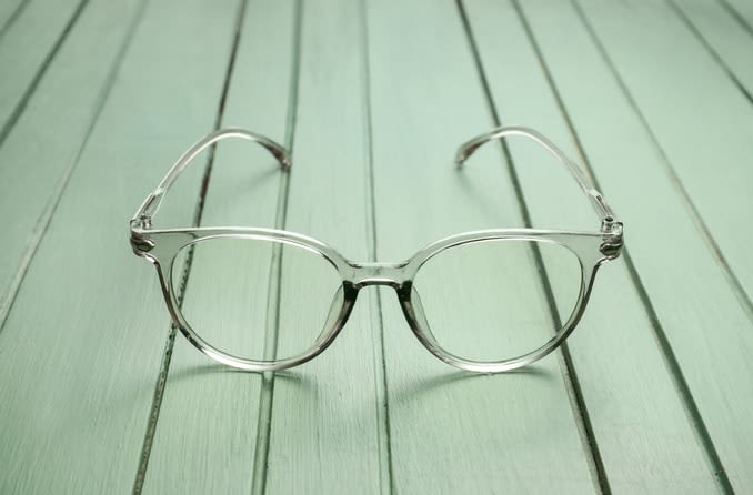A single pair of eyeglasses with translucent green frames resting on a jade-green table