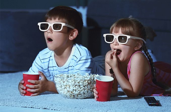 kids with popcorn watching a movie wearing 3d glasses