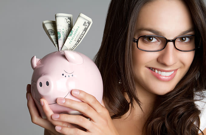 woman wearing glasses holding a piggy bank with money