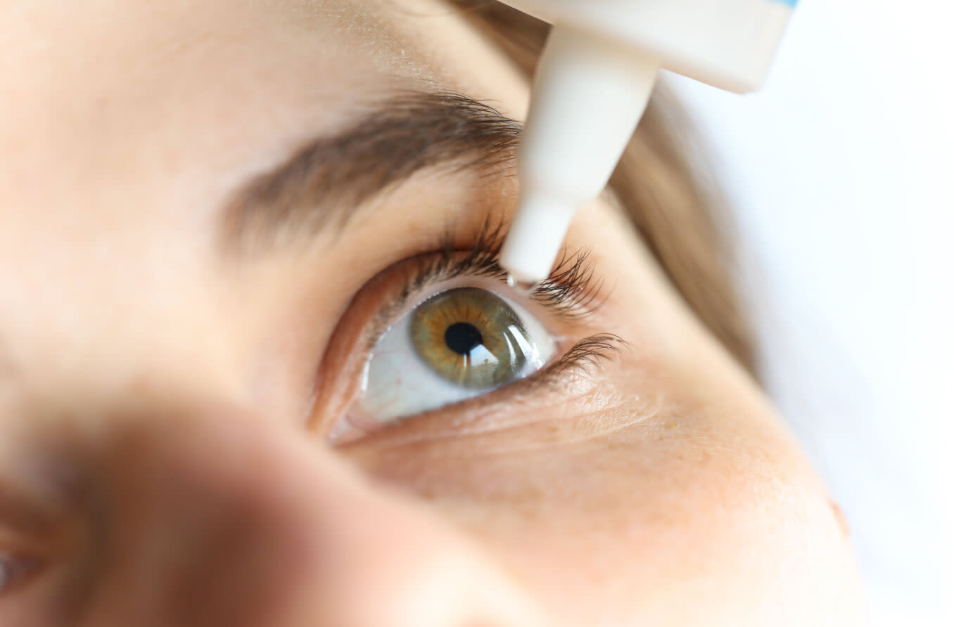 Close-up of young woman applying eye drop.