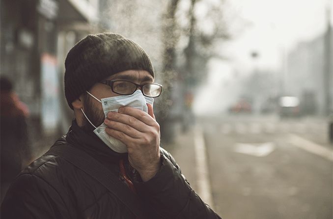 man wearing eyeglasses and covering his mouth being affected by air pollution