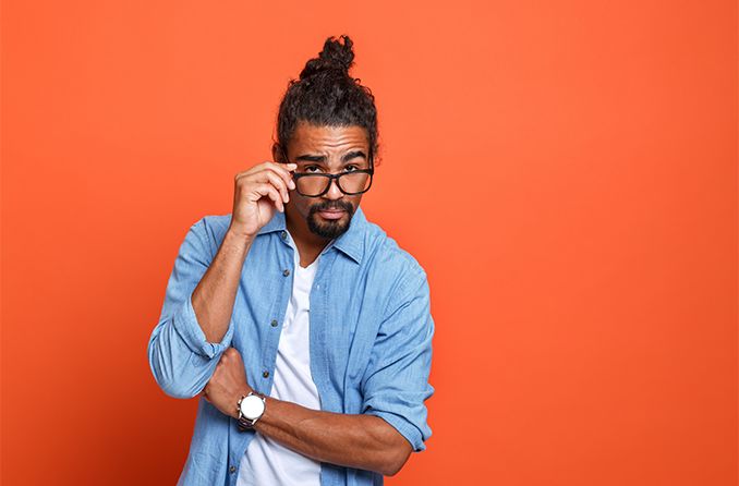 homme regardant par-dessus des lunettes sur fond orange