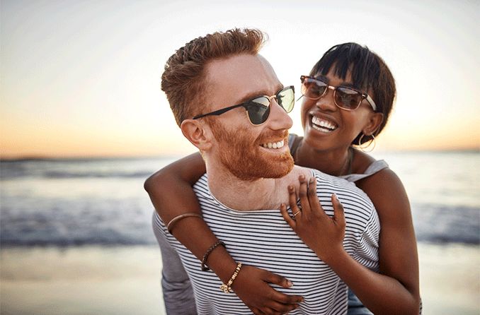 man and woman on beach wearing sunglasses