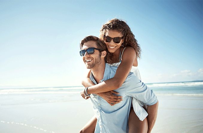 couple on beach wearing Foster Grant sunglasses