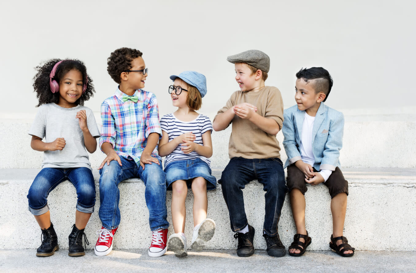 Group of diverse kids with glasses on, sitting on a bench.