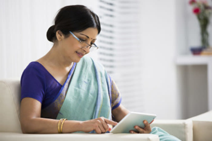 An Indian woman reading on a digital tablet - India