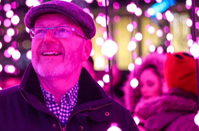 Middle-aged man wearing glasses looking at holiday lights