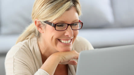 Middle aged woman wearing glasses looking at laptop computer