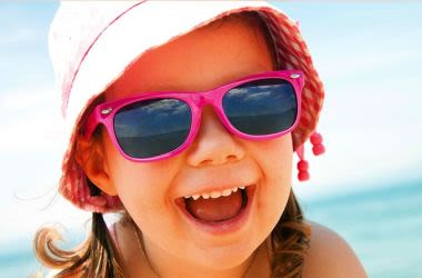 child wearing sunglasses and sun hat at the beach