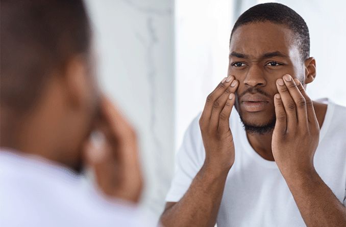 man with glassy eyes looking in the mirror