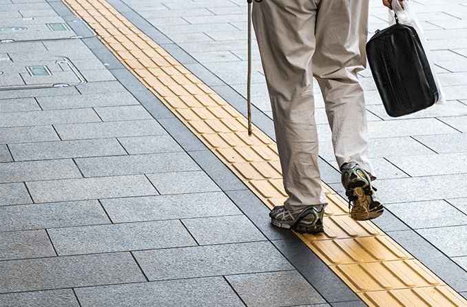 blind person walking along tactile paving