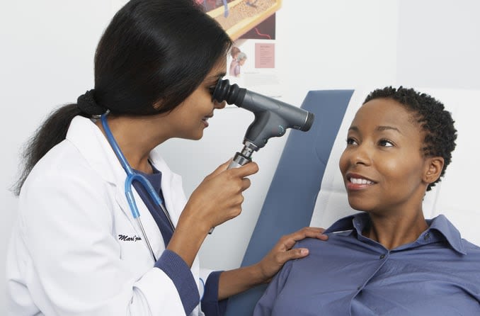 An ophthalmologist uses a small device to view her patient's eyes more closely.