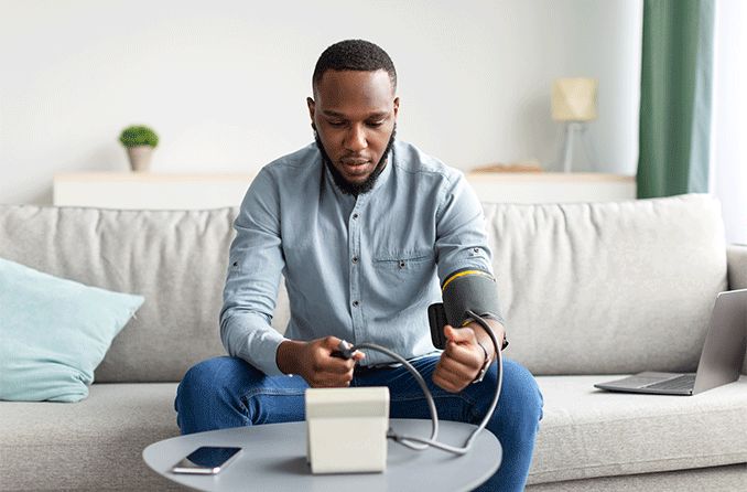 man with hypertension taking his blood pressure