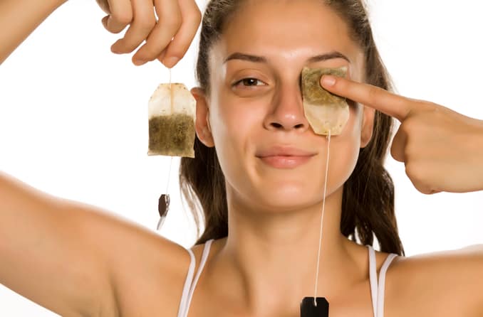 Woman using tea bags as cool compresses for her eyes