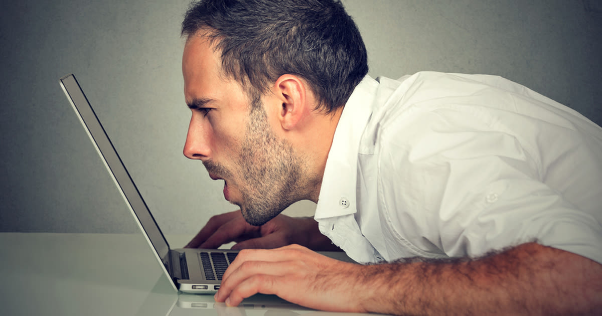 l'homme plisse les yeux à l'écran d'ordinateur portable sans lunettes de lecture